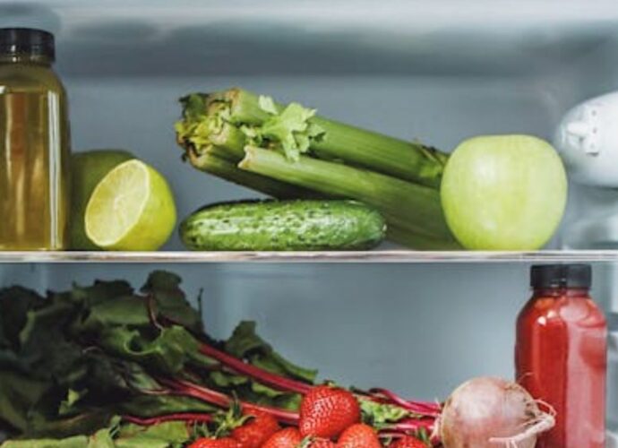 Ogórek na półce w lodówce obok selera naciowego, cytryny i cebuli