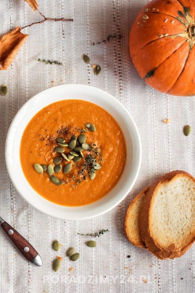 Krem z dyni podany z prażonymi pestkami dyni, tymiankiem i grzankami