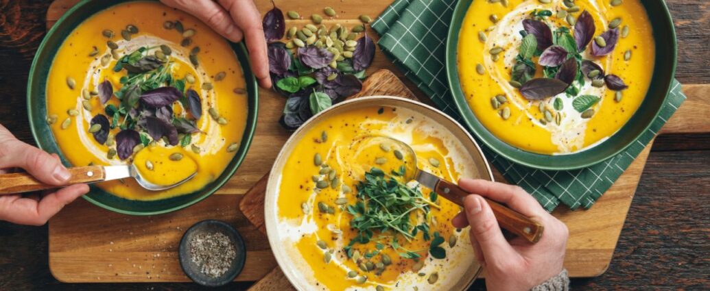Zupa dyniowa podana z dodatkiem pestek słonecznika, świeżej bazylii i śmietanki