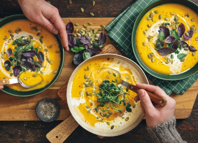 Zupa dyniowa podana z dodatkiem pestek słonecznika, świeżej bazylii i śmietanki