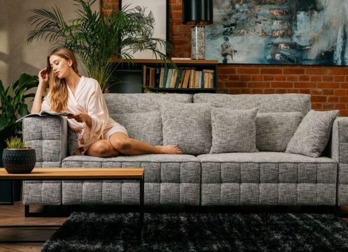 Kobieta czytająca magazyn na szarej sofie