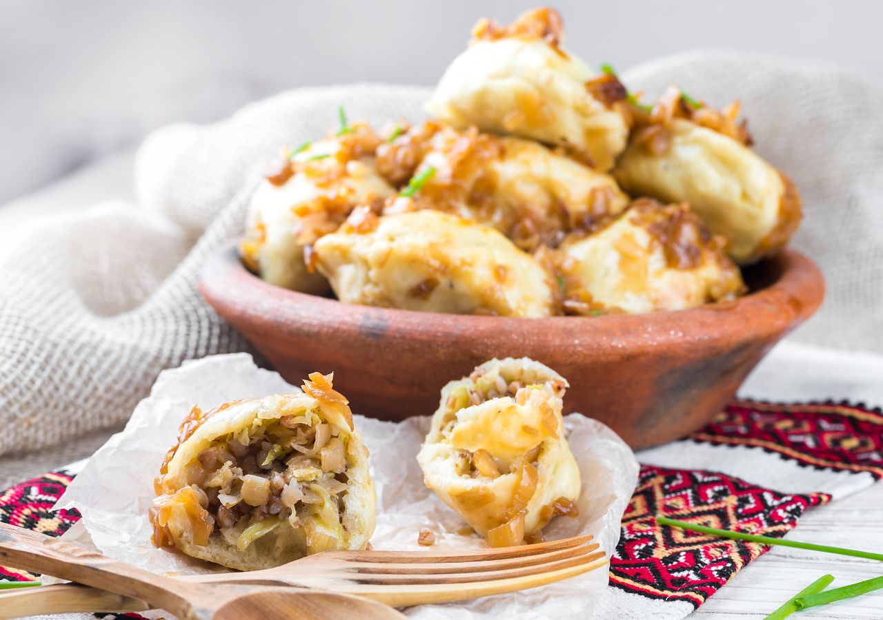Miska z pierogami z kapustą oraz przekrojony pieróg z nadzieniem z kapusty