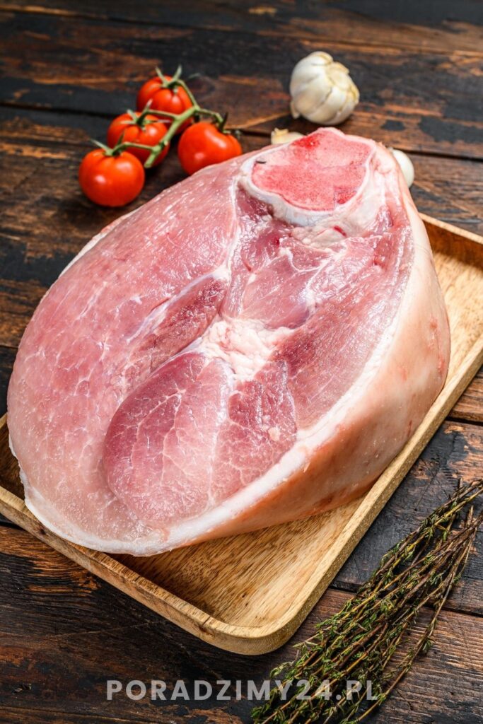 Surowa golonka wieprzowa na drewnianej tacy z pomidorkami