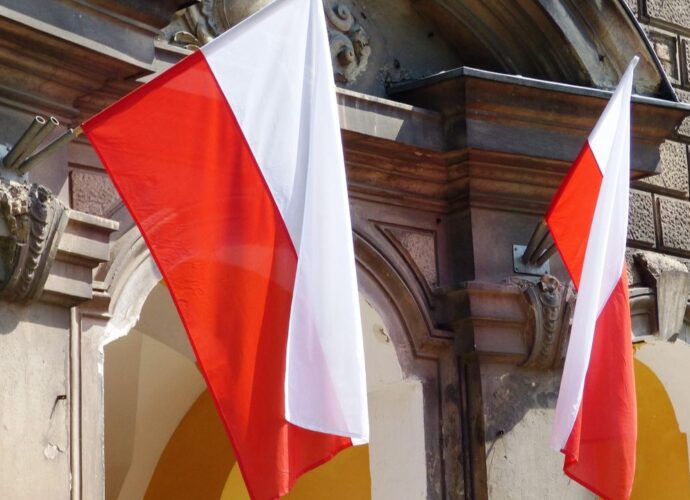 Polskie flagi wiszące nad wejściem do budynku