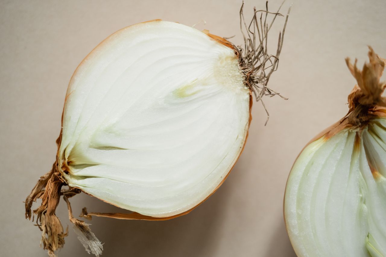 Przygotowanie celubil do krojenia w piórka po francusku. Cebula z łupiną przecięta na połówki
